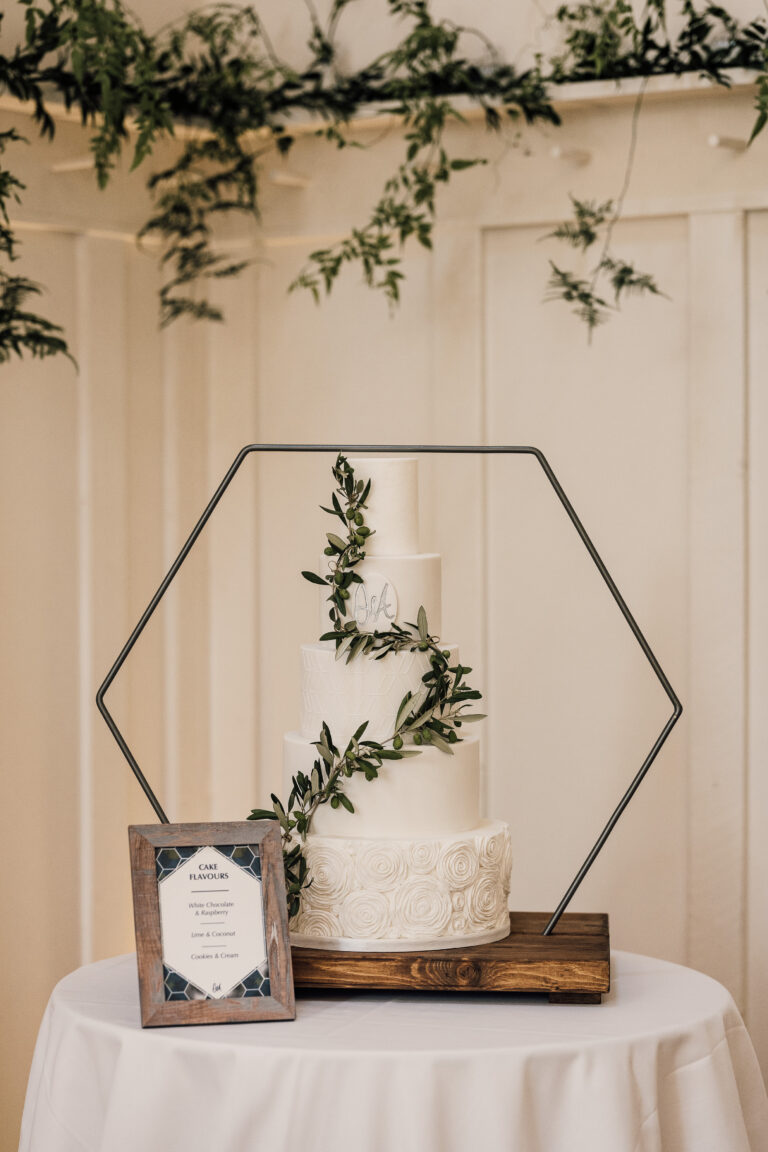 Wedding cake, dressed in foliage with a hexagon frame.