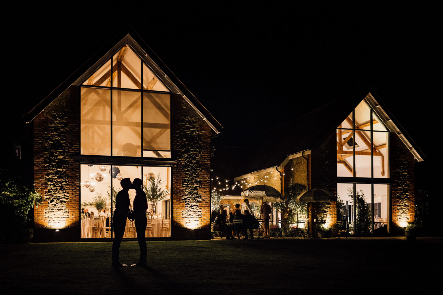 Same sex wedding. Venue at night with the Grooms sharing a kiss.