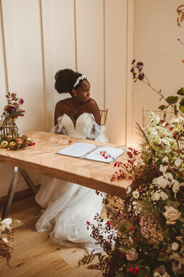 Maya + Adam glowing bride looks out at the view of the gardens at Millbridge Court